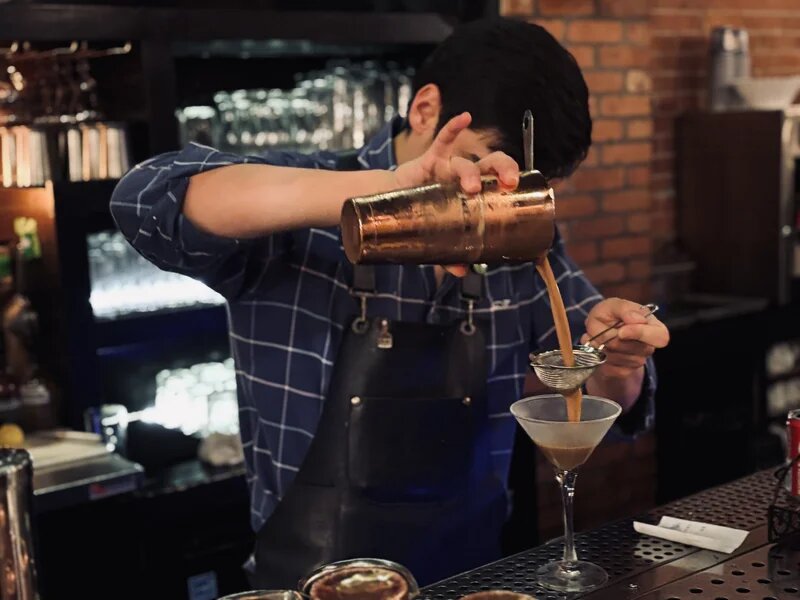 Bartender crafting a signature cocktail with copper shaker at La Casa del Sol