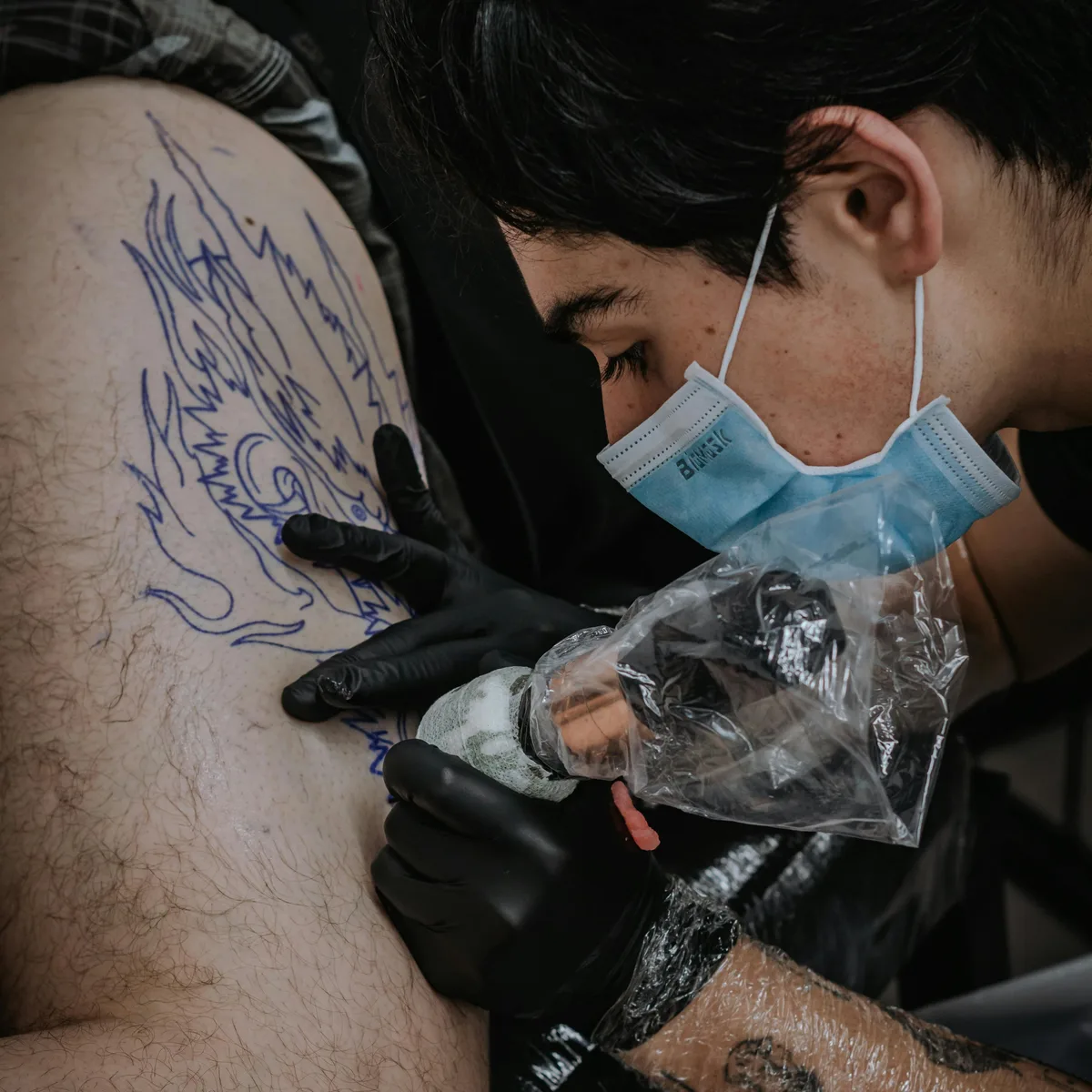 Artist executing bold traditional tattoo with precise black outline and saturated fill