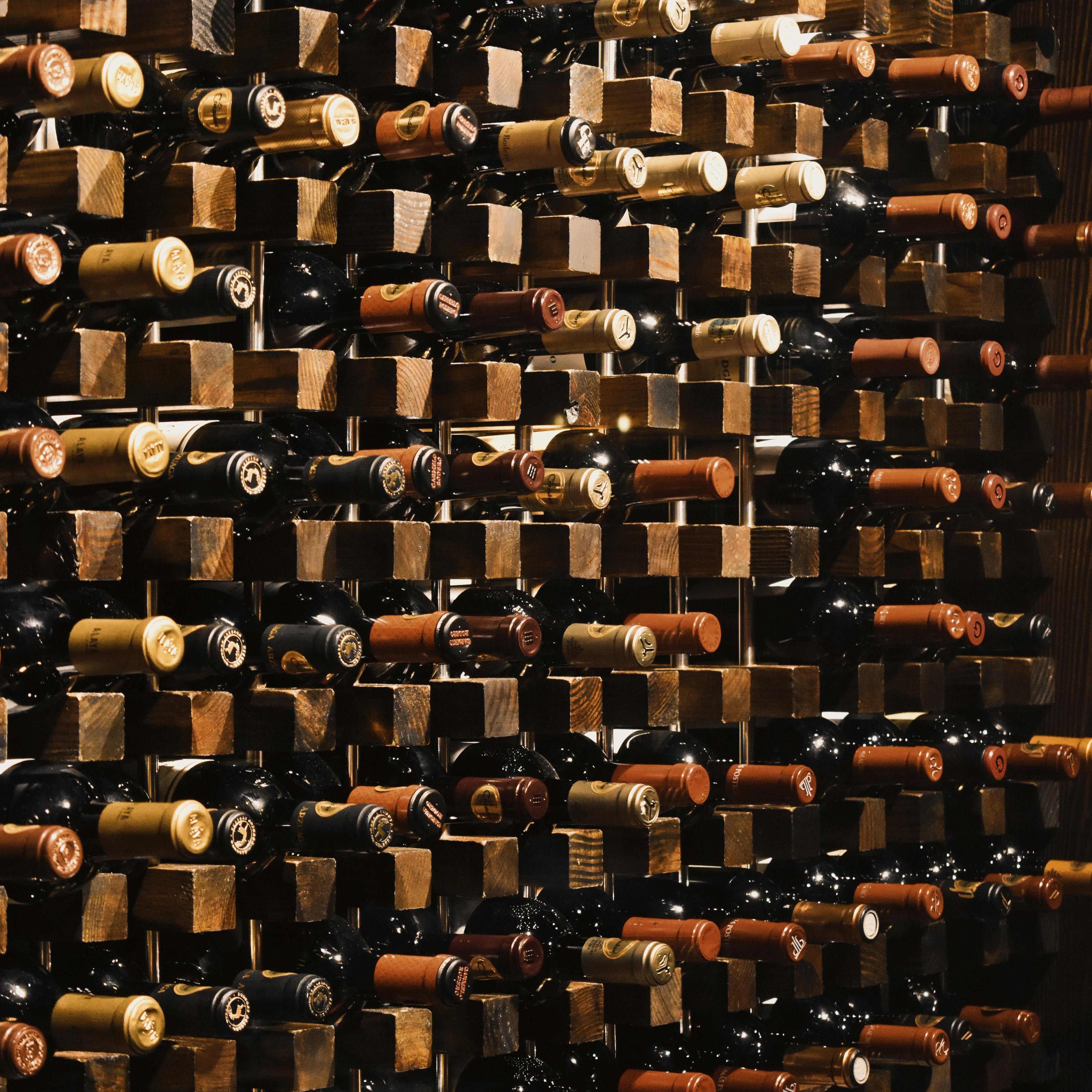Two crystal coupes on a polished oak bar — a pale gold Chardonnay beside a deep ruby Pinot Noir